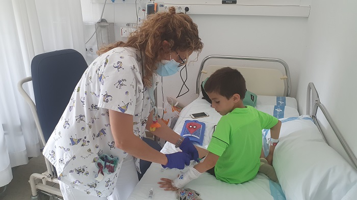 Una infermera posant medicació a un nen amb la Superbox darrera