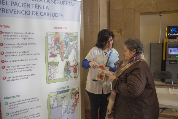Professional d'infermeria parlant explicant la campanya de sensibilització sobre la prevenció de les caigudes a una usuaria.