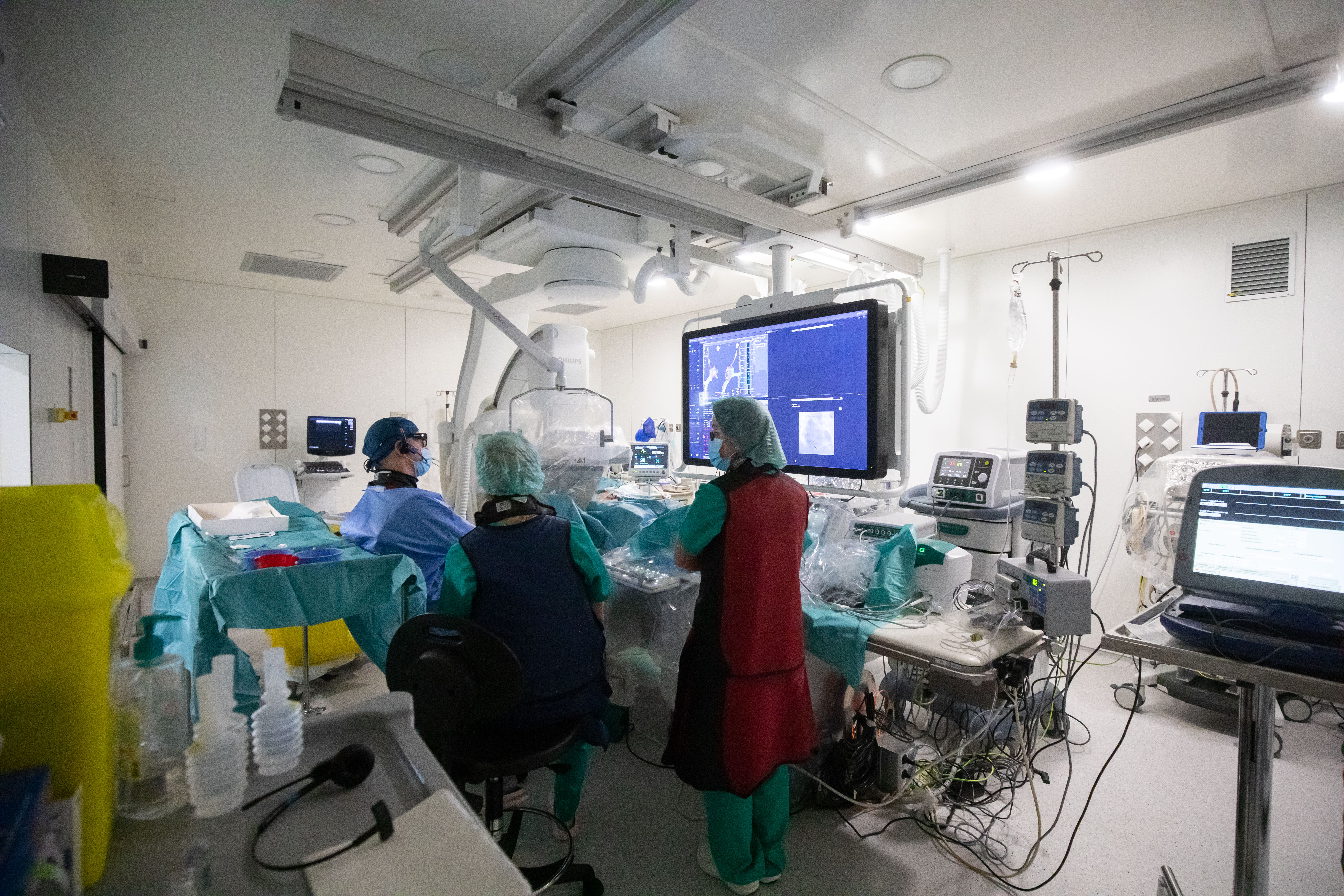 Una imatge de la sala d'electrofisiologia amb tres dels professionals que hi treballen.