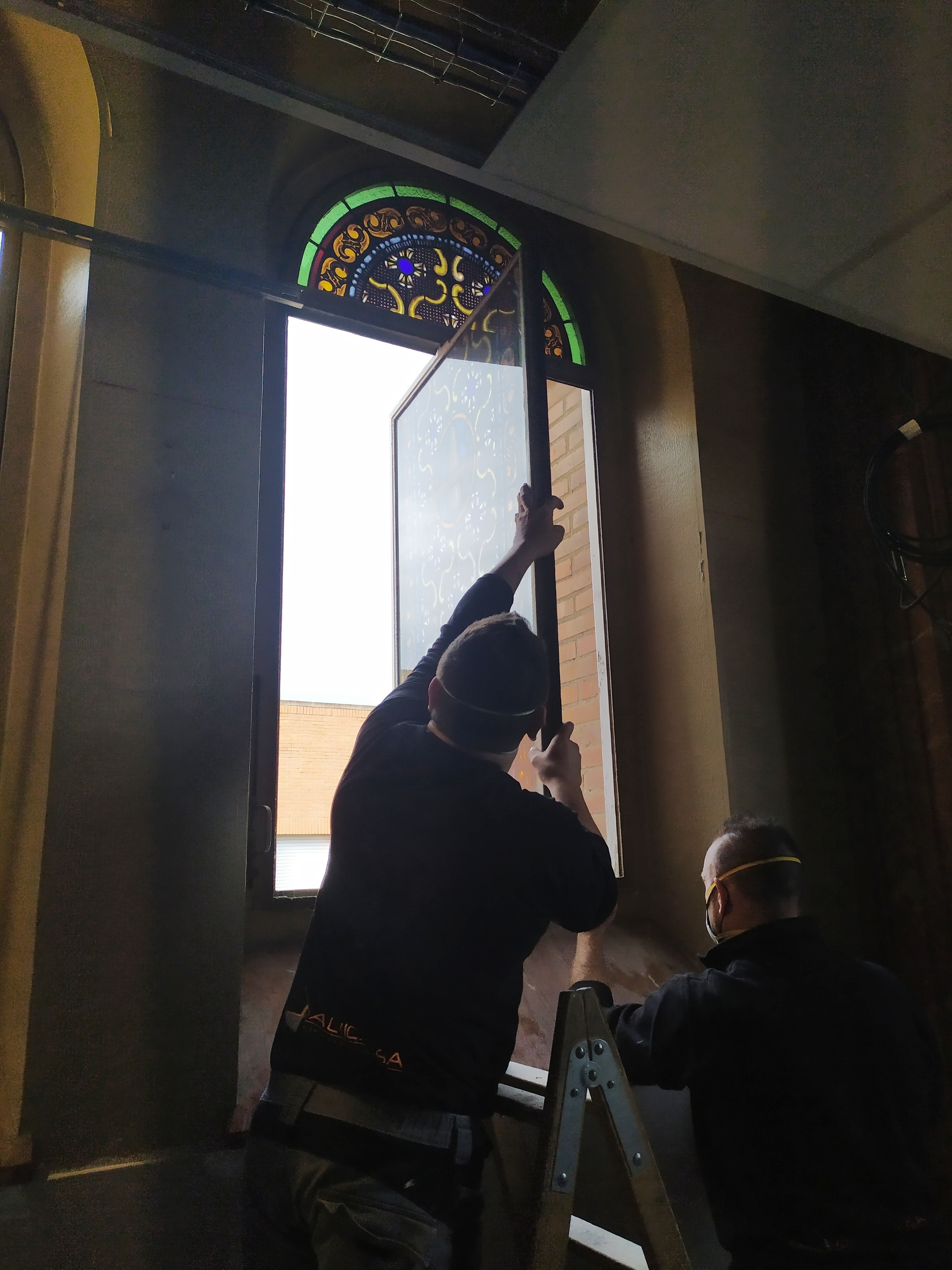 Dos operaris retiren els vitralls de l'antiga capella