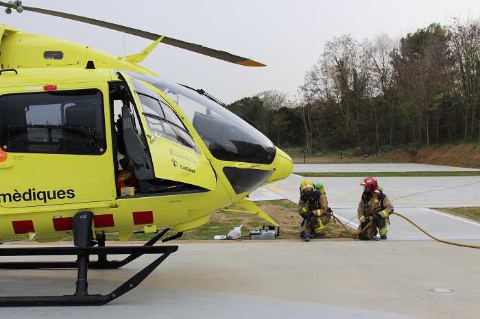 Els bombers simulen que apagaguen el foc de l'helicòpter, durant l'exercici de simulació.