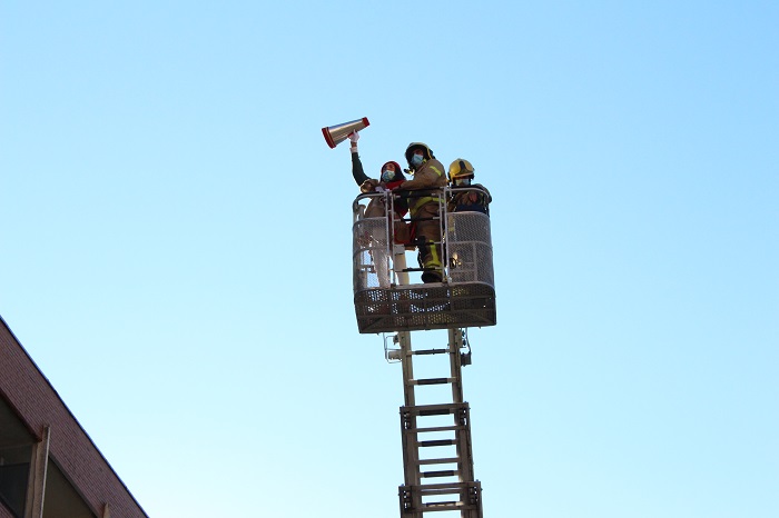 Un dels patges amb els Bombers enfilat a la cistella de la grua