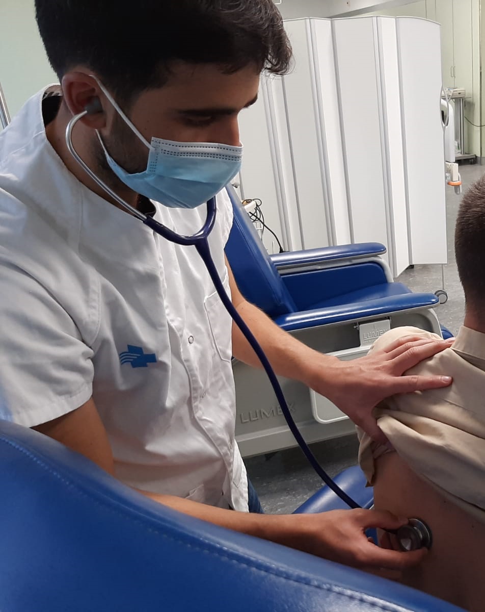 Professional de la medicina auscultant a una persona participant abans de l'administració de la vacuna HIPRA Covid-19_2