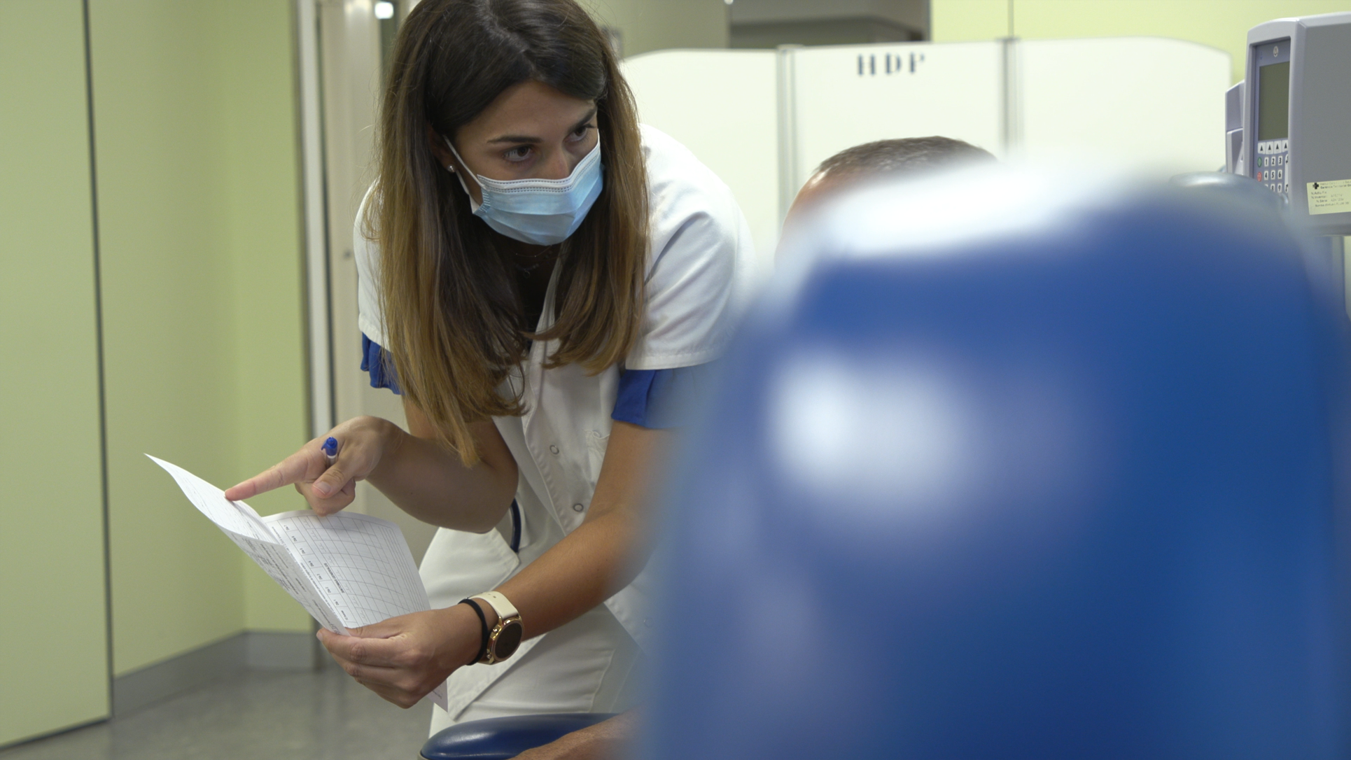 Professional de la medicina explicant el procediment del procés de monitorització a una de les persones participants de l'estudi de la vacuna HIPRA Covid-19