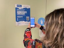 Imatge d'una noia mirant un cartell sobre el procés participatiu per incorporar la veu de la ciutadania en el projecte del nou Campus de Salut de la Regió Sanitària Girona 